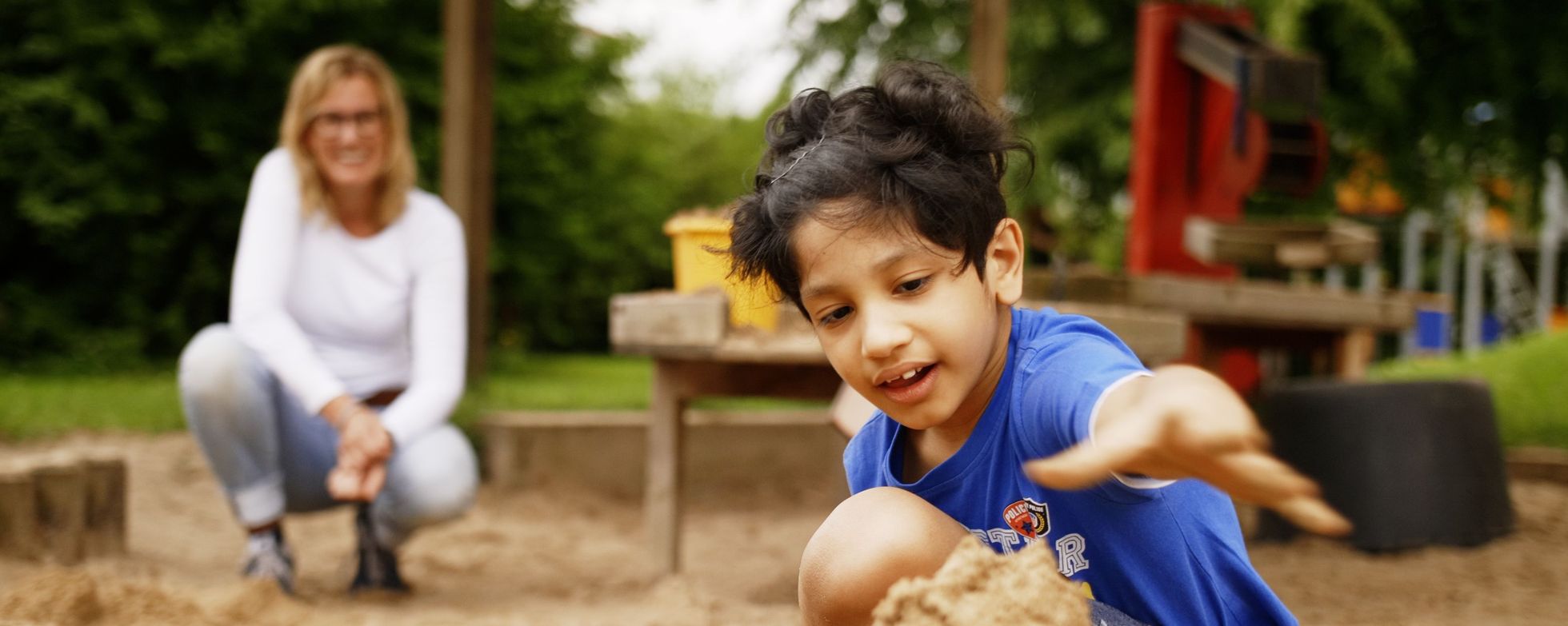 Spielender Junge im Vordergrund, Erzieherin weiter hinten. Spielender Junge im Vordergrund, Erzieherin weiter hinten.